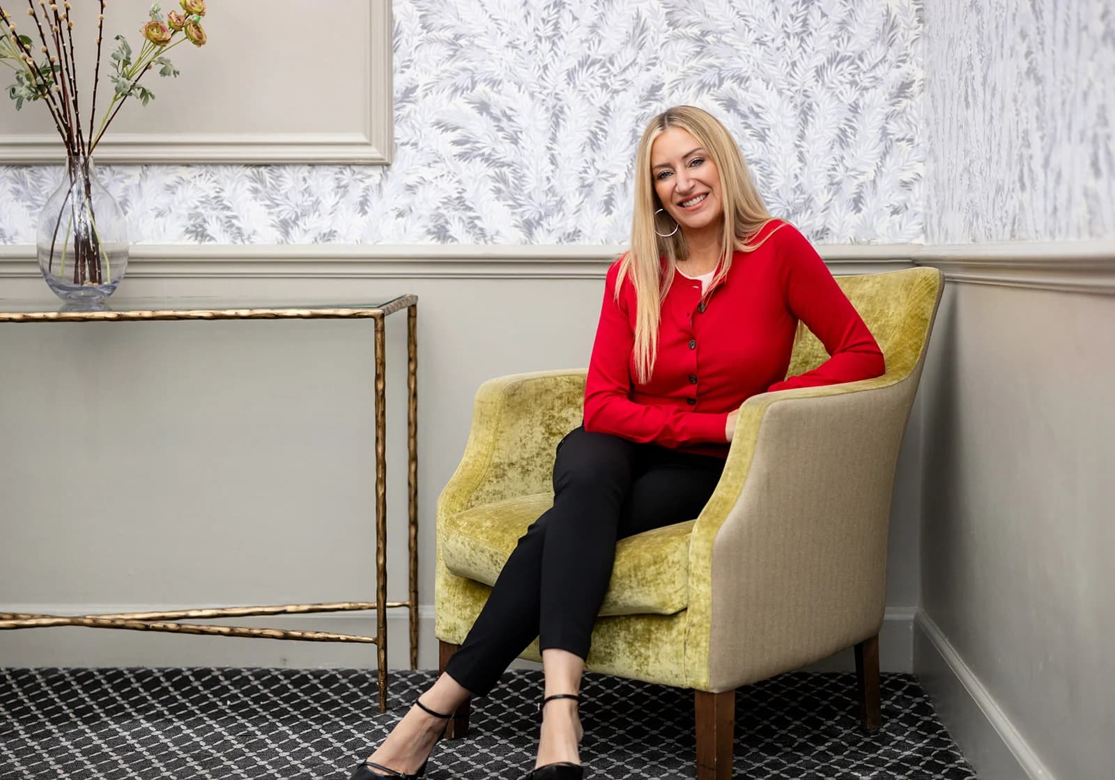 Gemma in a red cardigan, seated in an armchair at the Maids Head Hotel